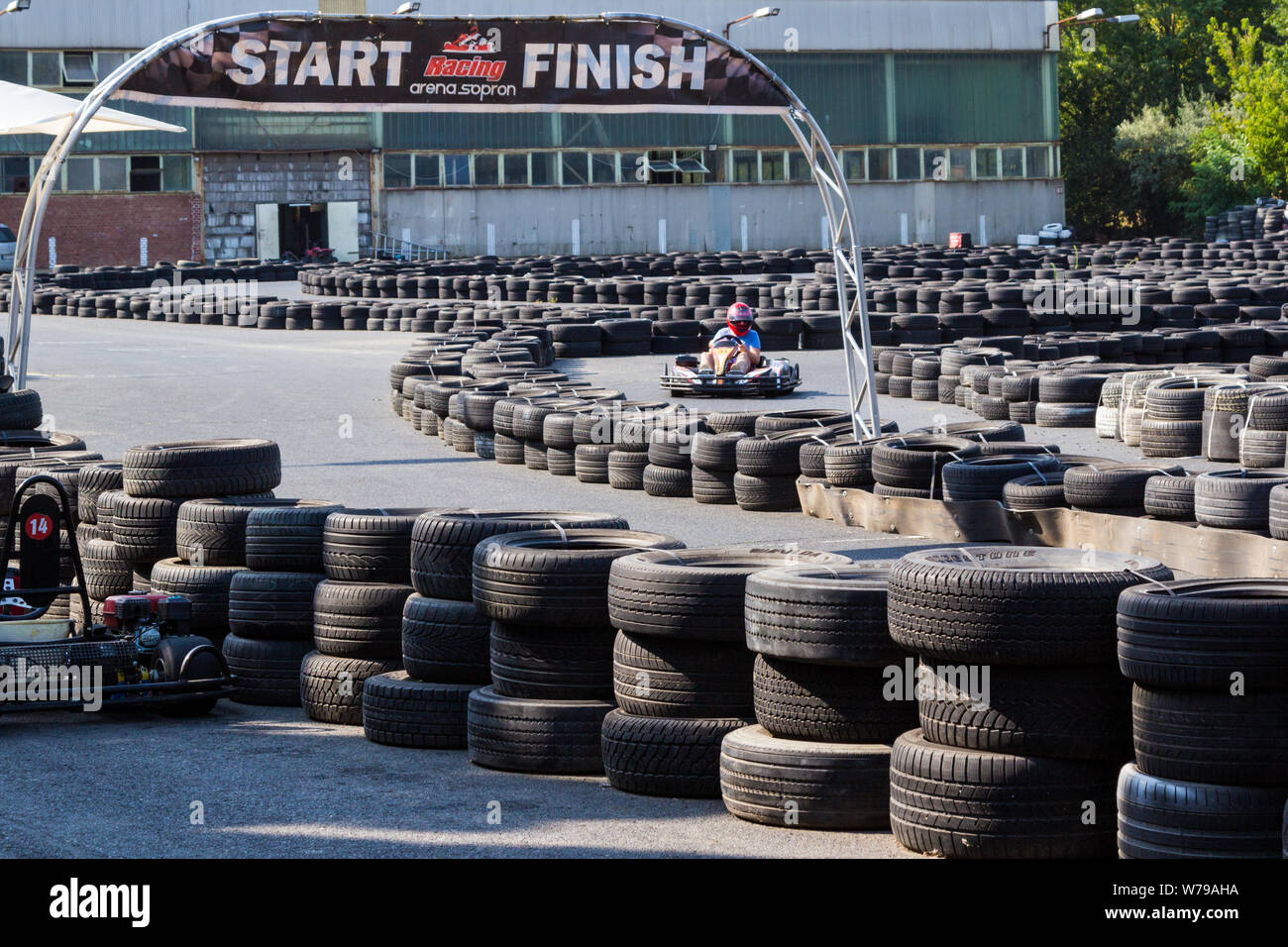 Go-kart passando accanto iniziare e terminare il banner tra barriere di pneumatici Foto Stock