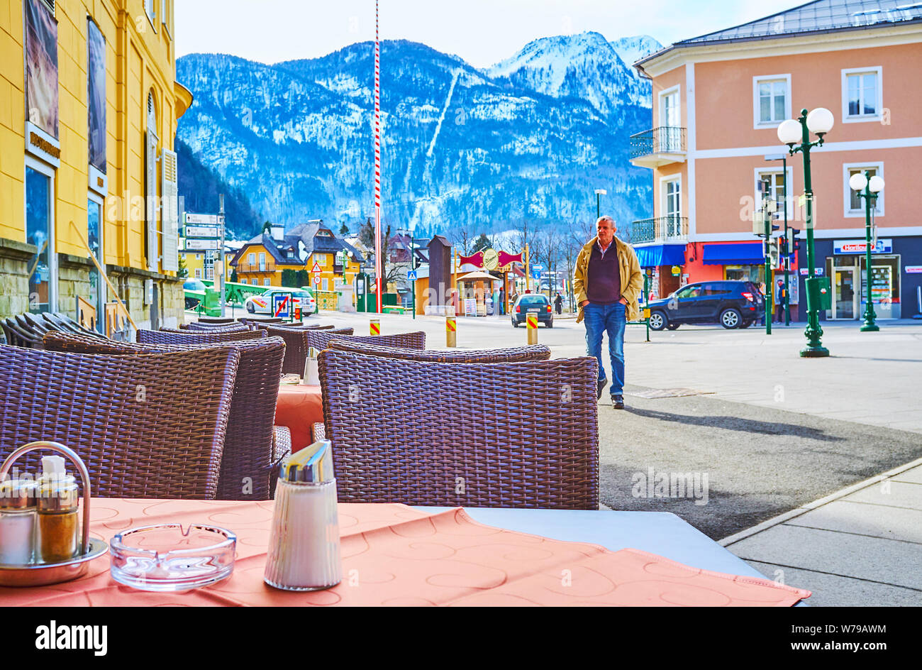 BAD Ischl Austria - 26 febbraio 2019: i tavoli del ristorante all'aperto in Pfargasse street sulla città vecchia con una vista su edifici colorati e il Monte Kat Foto Stock