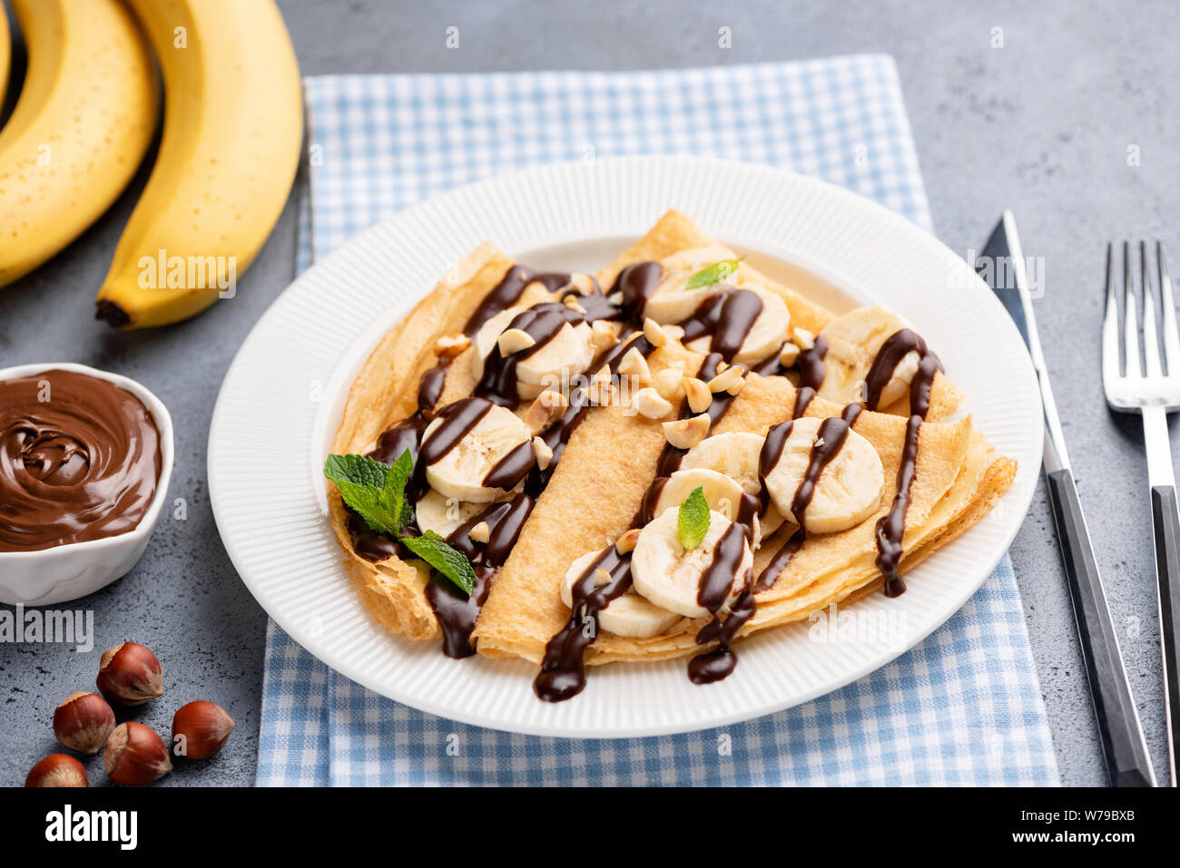 Gustosa crêpe con banana e salsa al cioccolato sulla piastra bianca. Francese frittelle sottili o russo blini per dessert Foto Stock