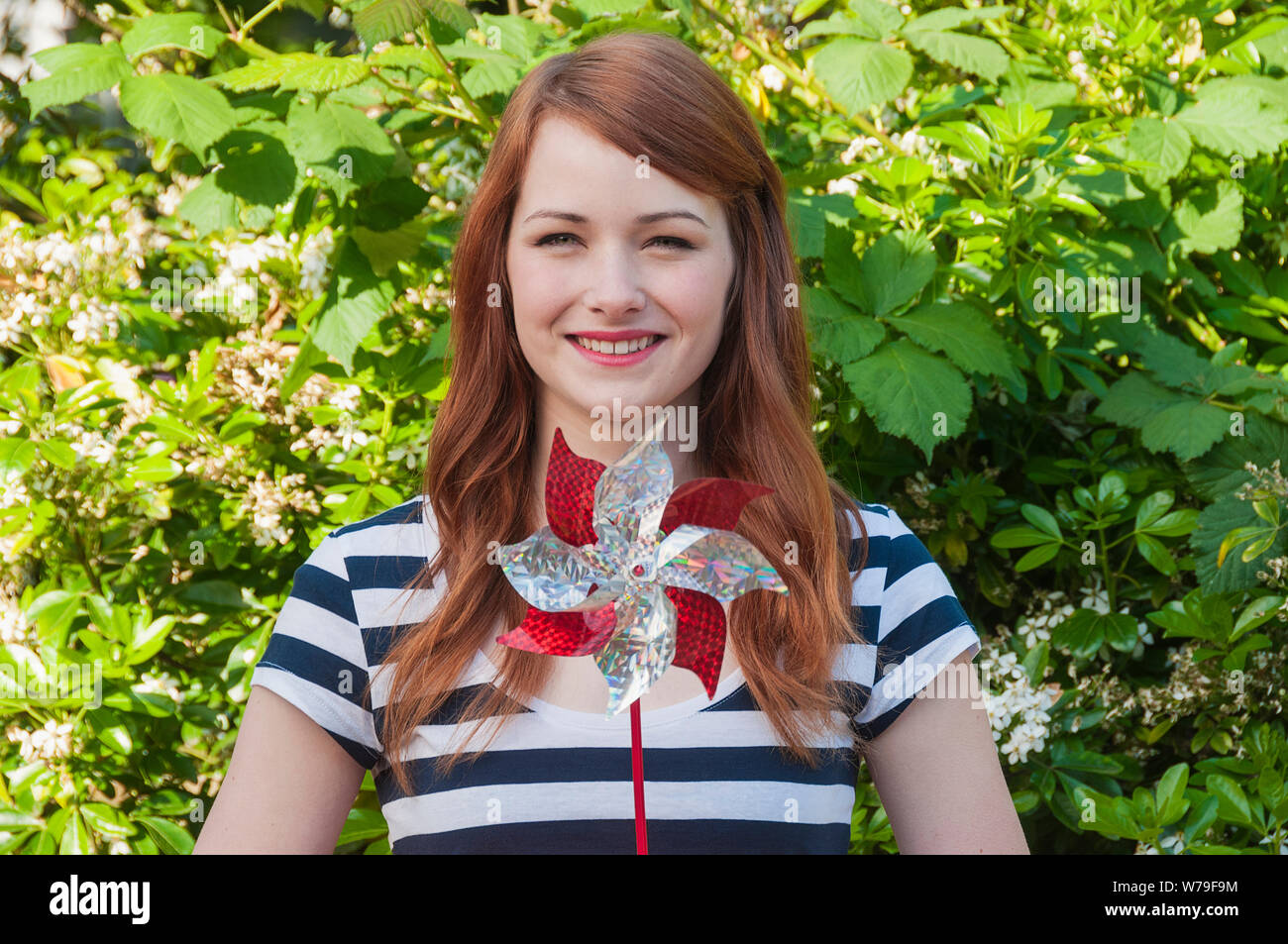Una giovane donna con i capelli rossi tenendo una girandola. Foto Stock