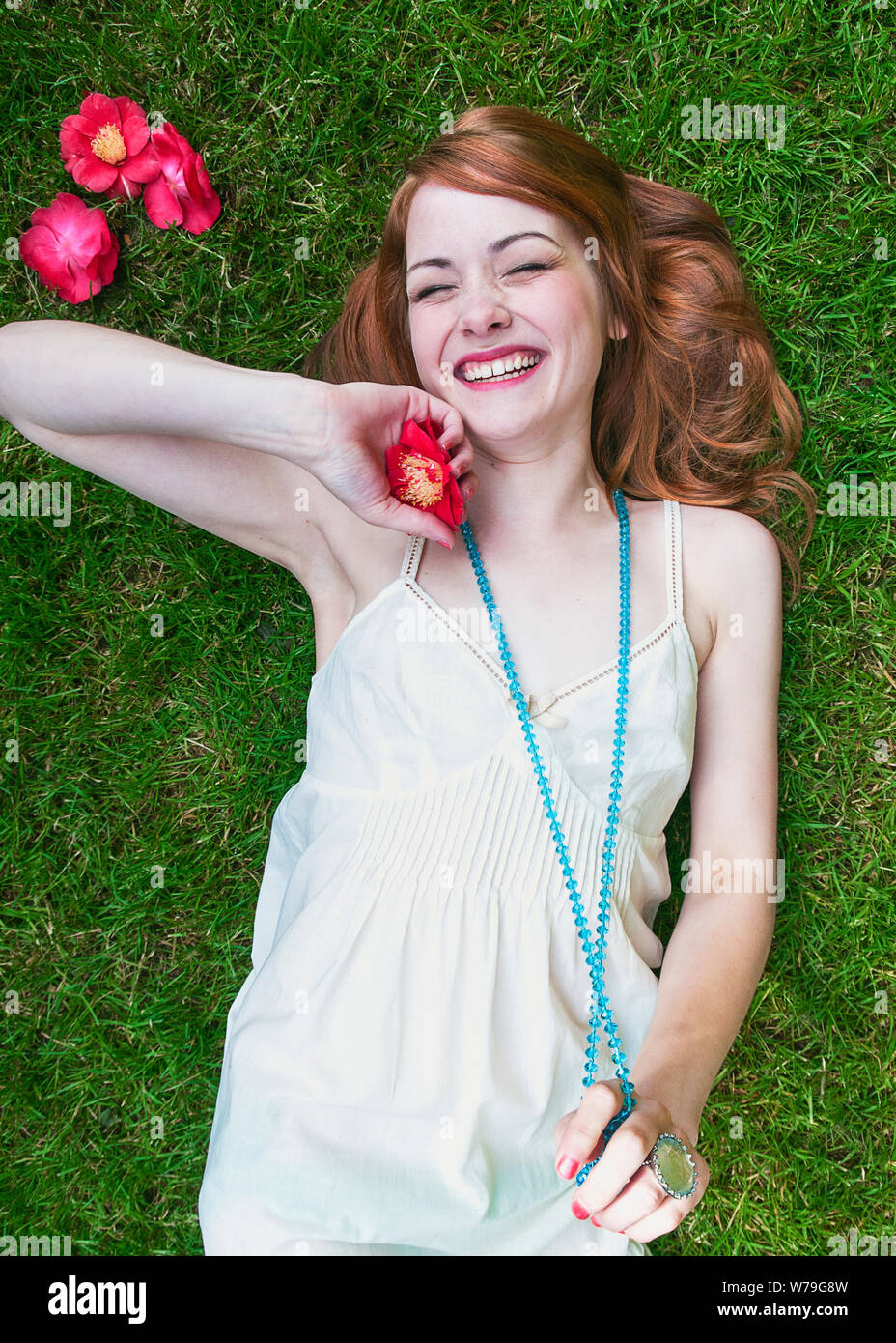 Una giovane donna posa sull'erba a ridere. Foto Stock