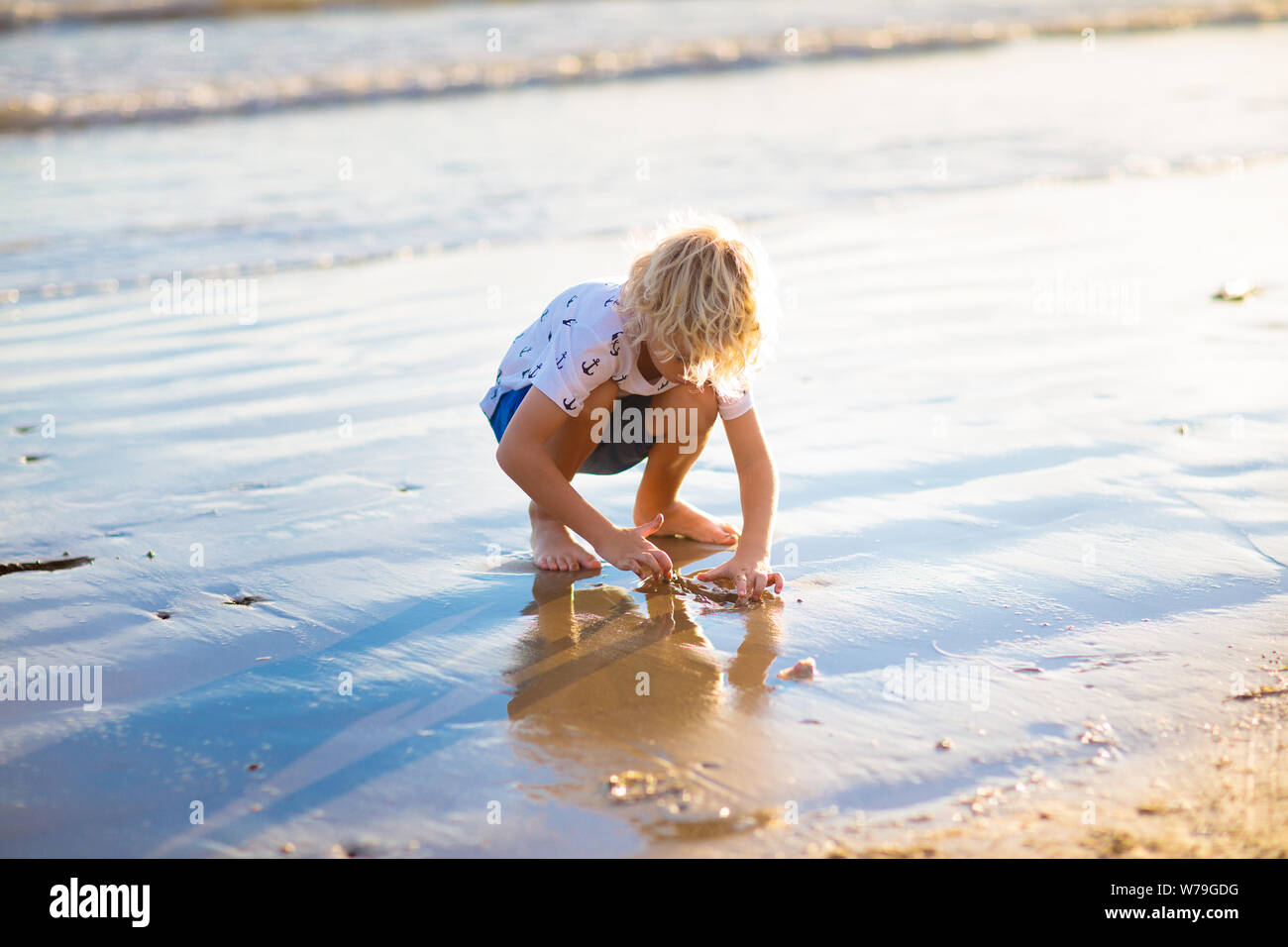 Bambini che giocano sulla spiaggia tropicale. I bambini giocano in mare in estate la vacanza di famiglia. Sabbia e acqua giocattoli, protezione solare per il bambino. Little Boy diggin Foto Stock