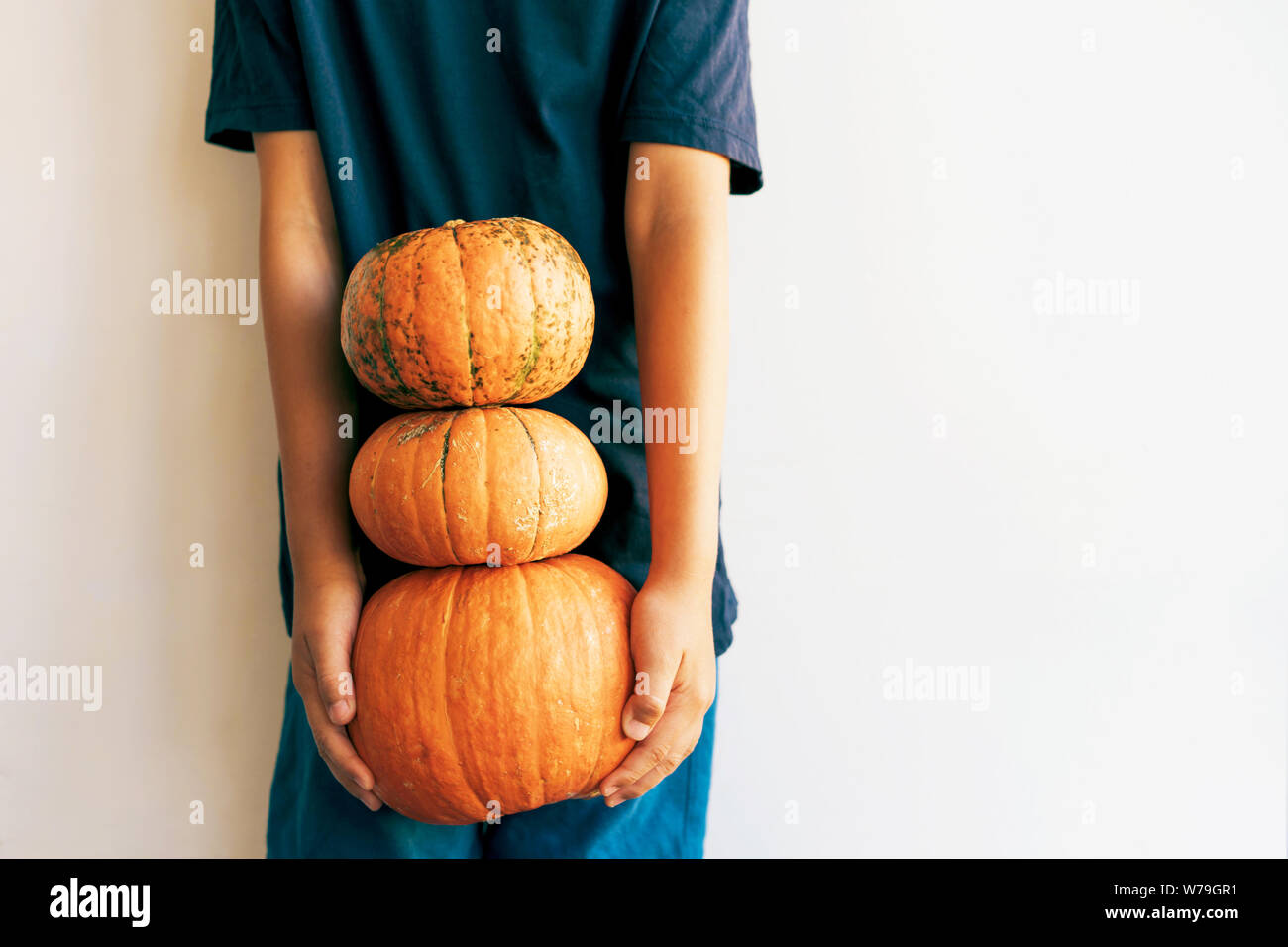 Torre di tre varietà di zucche nelle mani di un bambino Foto Stock