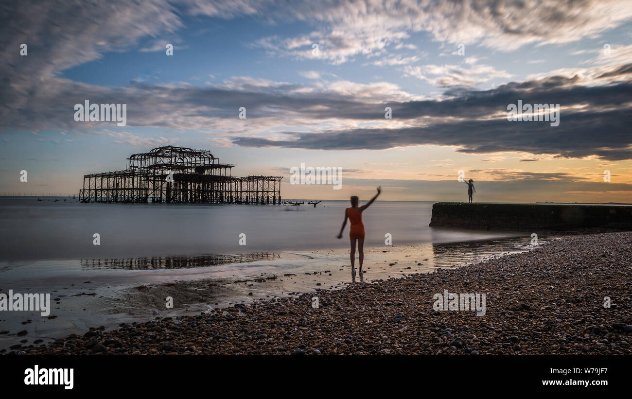 Due figure umane sulla spiaggia di Brighton al tramonto. Foto Stock