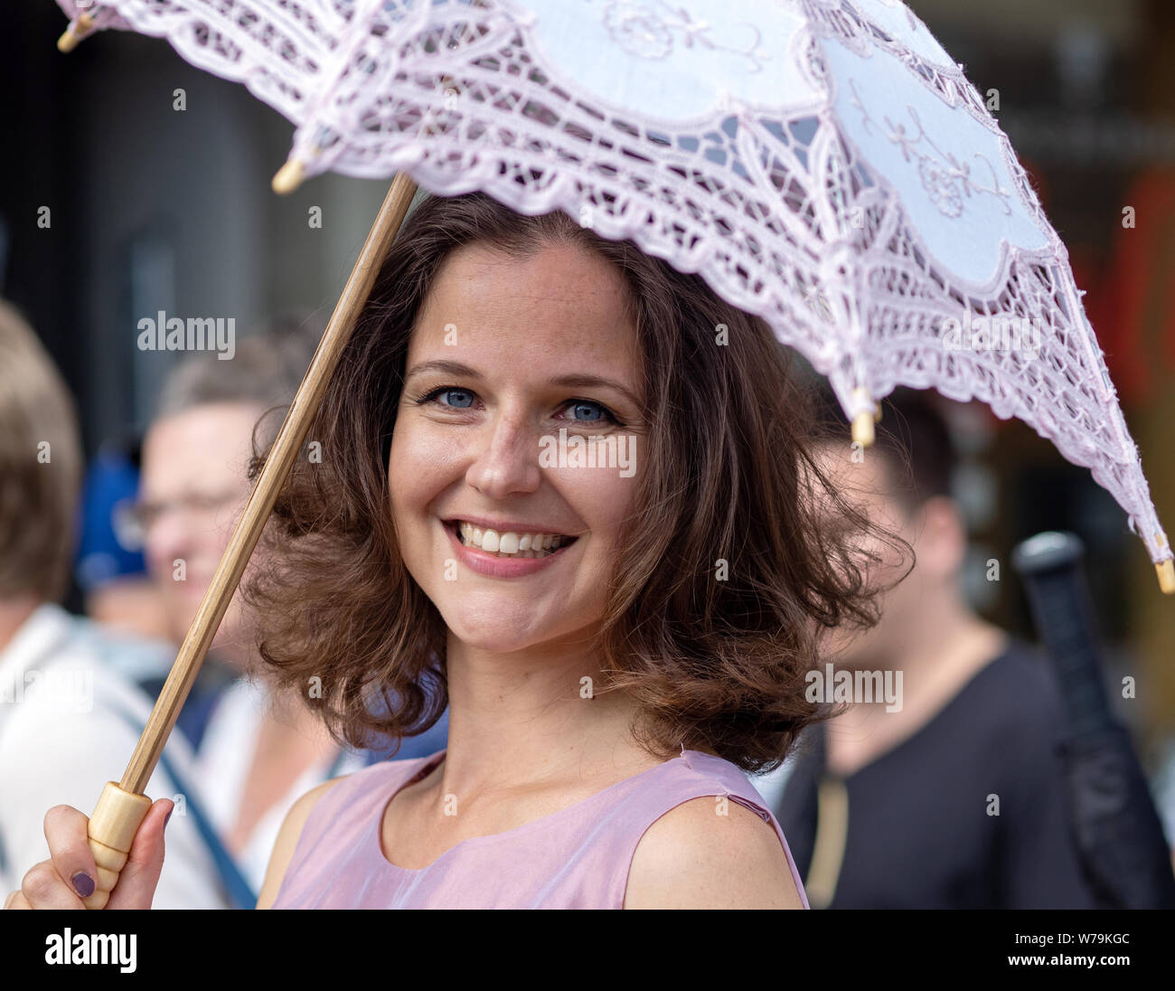 Femmina performer di strada con il volto sorridente e bianco brolly, Edinburgh Festival Fringe 2019 - Il Royal Mile di Edimburgo, Scozia, Regno Unito. Foto Stock