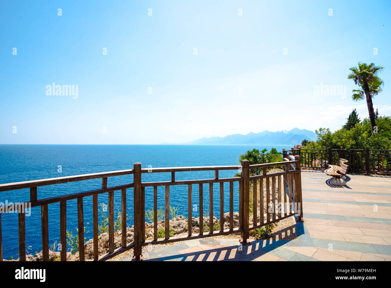 Una terrazza panoramica che si affaccia sul mare blu. Sul sito è un banco per il riposo e il tracking con una bellissima vista. Le palme crescono intorno. Foto Stock