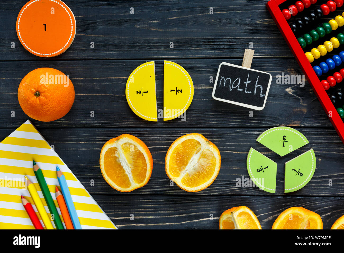 Сolorful math frazioni e arance come un campione in legno scuro o di sfondo tabella. Interessante creative matematica divertente per i bambini. Istruzione, torna a schoo Foto Stock