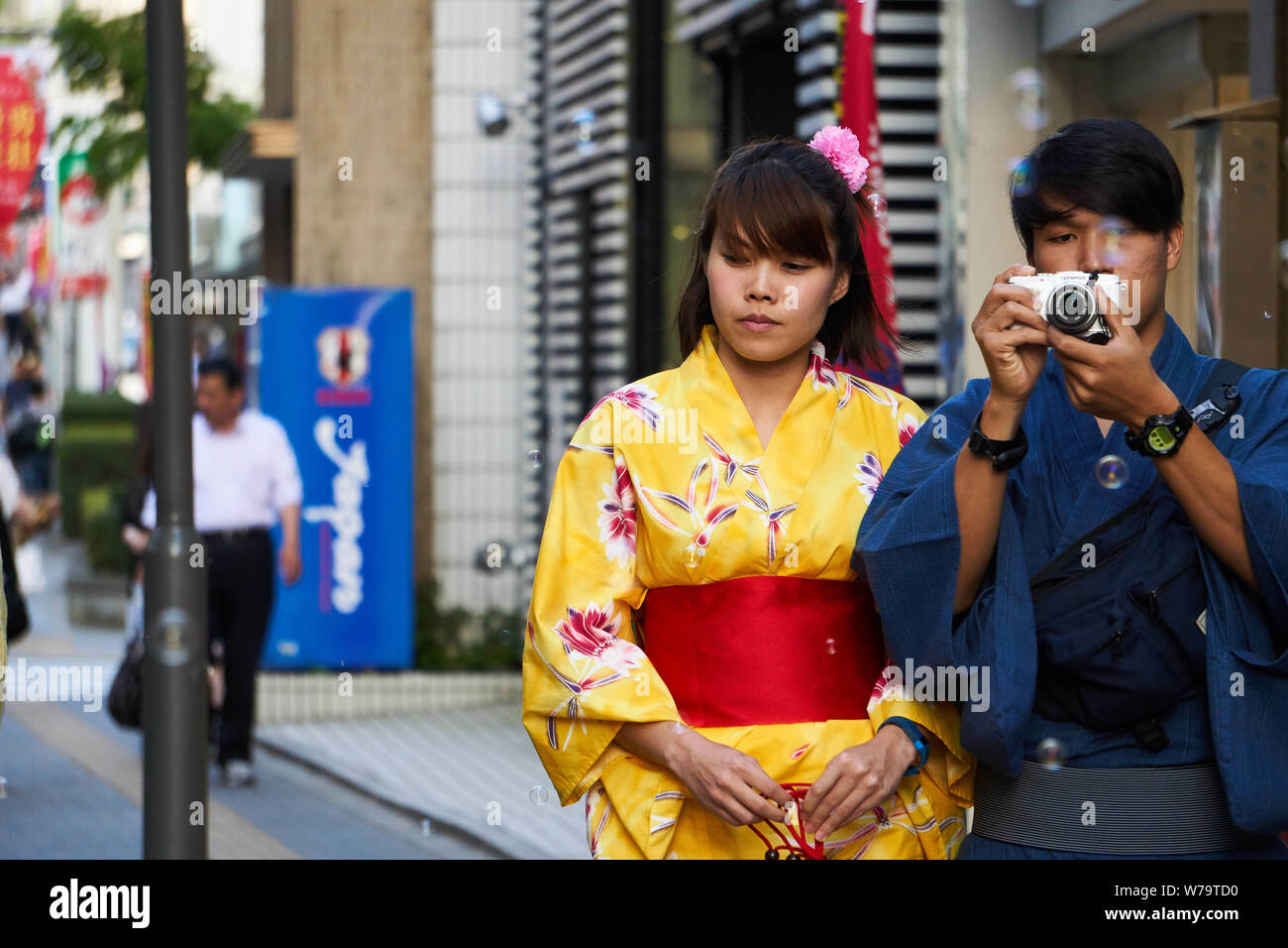 Una giovane giapponese l uomo e la donna giovane indossare uno yukata (kimono  estivo) camminare intorno Akita. L'uomo è di scattare una foto di bolle di  aria Foto stock - Alamy