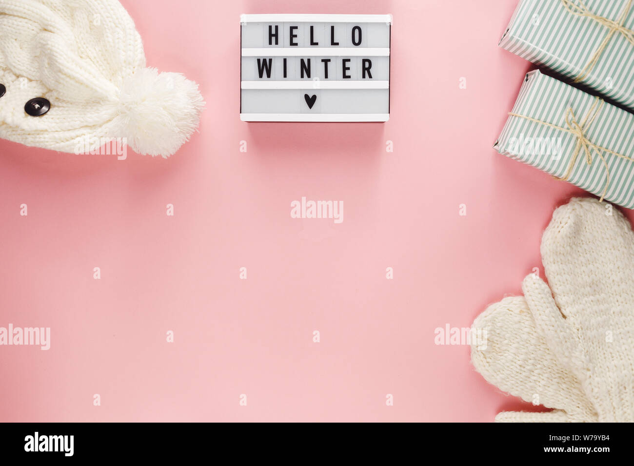 Concetto di Natale lay piatto. Caldo e accogliente bianco inverno maglione abbigliamento, Lightbox e decorazioni di Natale cornice rosa su sfondo pastello Foto Stock