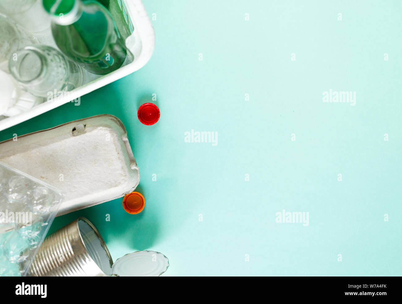Piatto di laici diversi rifiuti pronto per il riciclaggio su sfondo verde. Plastica, vetro, carta, lattine di lattina. Responsabilità Sociale, ecologia concetto di cura Foto Stock