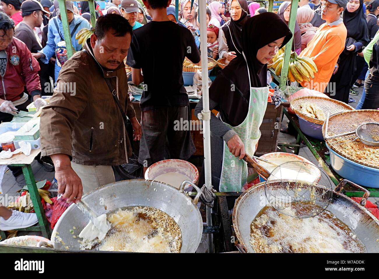 Jakarta, Indonesia - Agosto 2019 : un marito e moglie giovane sono spuntini di frittura in vendita nella propria cucina di strada stand. Foto Stock