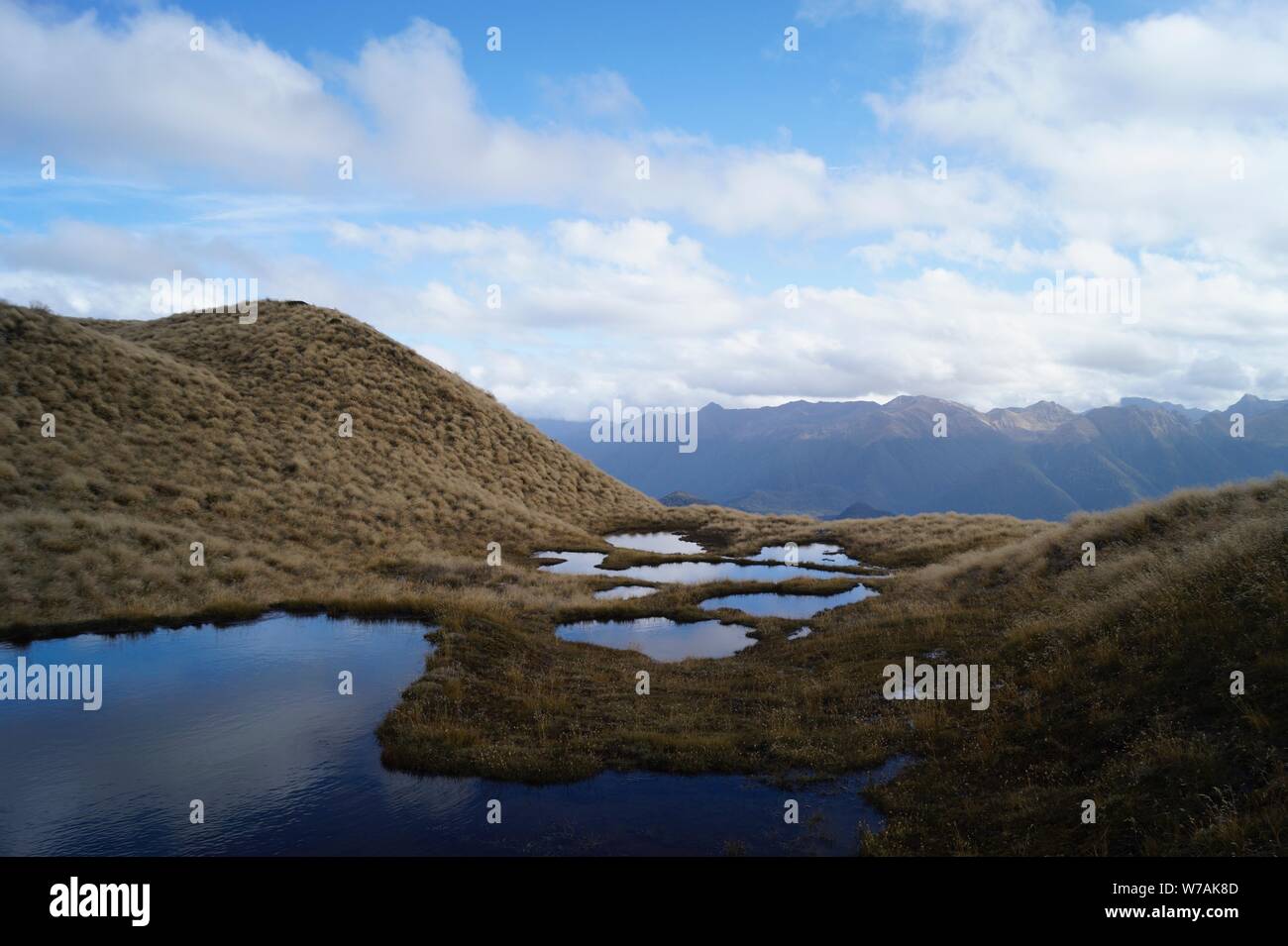 Il cielo si riflette mini laghi sulla sommità del Monte brucia a piedi via Foto Stock