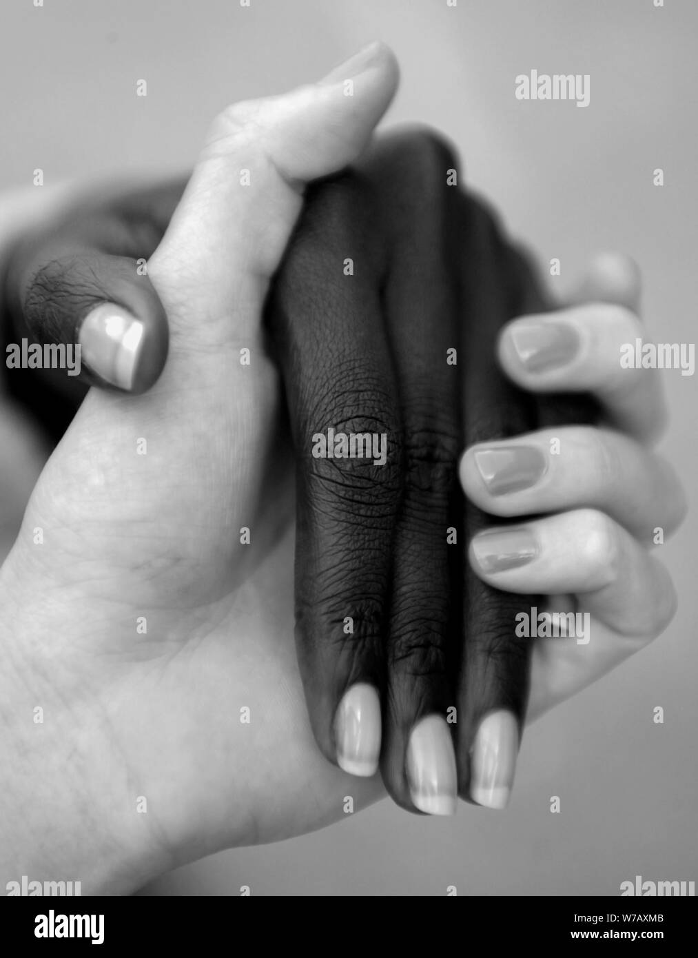 Le donne amici di diverse razze, africane ed europee, tenendo le mani. Entrambe le mani sono state ben curato Foto Stock
