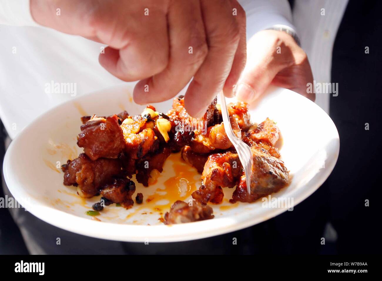 Un dipendente cinese mostra un piatto agrodolce costine realizzate da un auto stir-fried macchina sul display durante la seconda Cao egli Jing high-tech par Foto Stock
