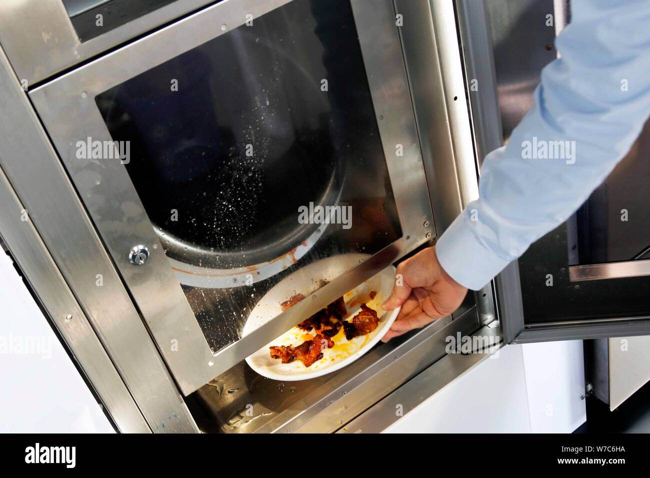 Un dipendente cinese prende un piatto agrodolce costine da un auto stir-fried macchina sul display durante la seconda Cao egli Jing high-tech Park e Foto Stock