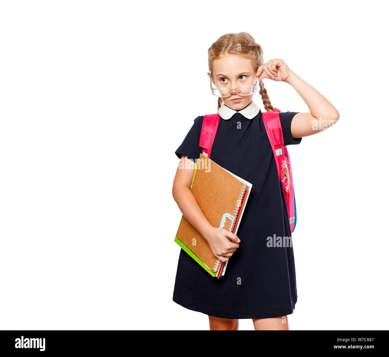 8 anni schoolgirl con uno zaino che indossano uniformi isolato permanente su uno sfondo bianco. Pronti per la scuola Foto Stock