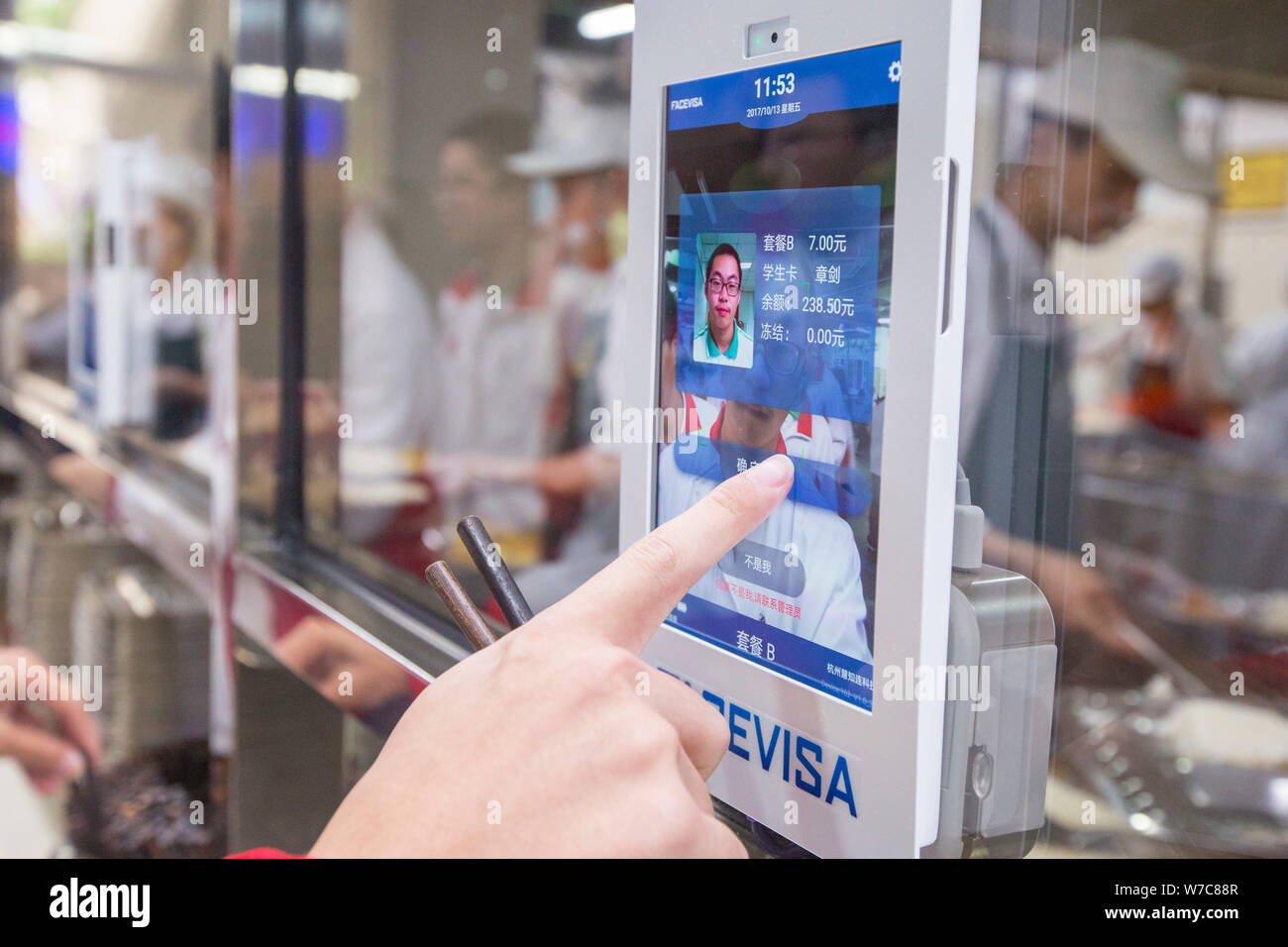 Uno studente conferma il pagamento come egli utilizza un riconoscimento facciale macchina per pagare il suo pasto in mensa al n. 11 Middle School di Hangzhou, ea Foto Stock