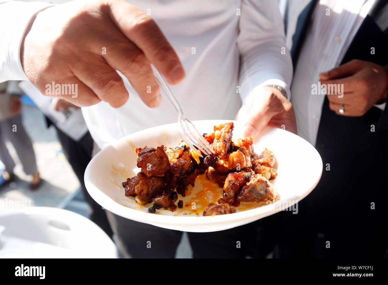 Un dipendente cinese mostra un piatto agrodolce costine realizzate da un auto stir-fried macchina sul display durante la seconda Cao egli Jing high-tech par Foto Stock