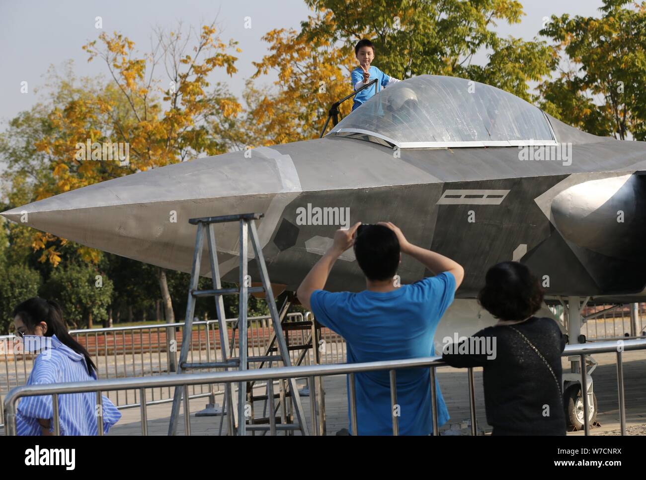 Un bambino prende le foto con il modello a grandezza del J-20 Stealth Fighter Aircraft cinese di PLA (popoli dell Esercito di Liberazione) Air Force costruito da Chine Foto Stock