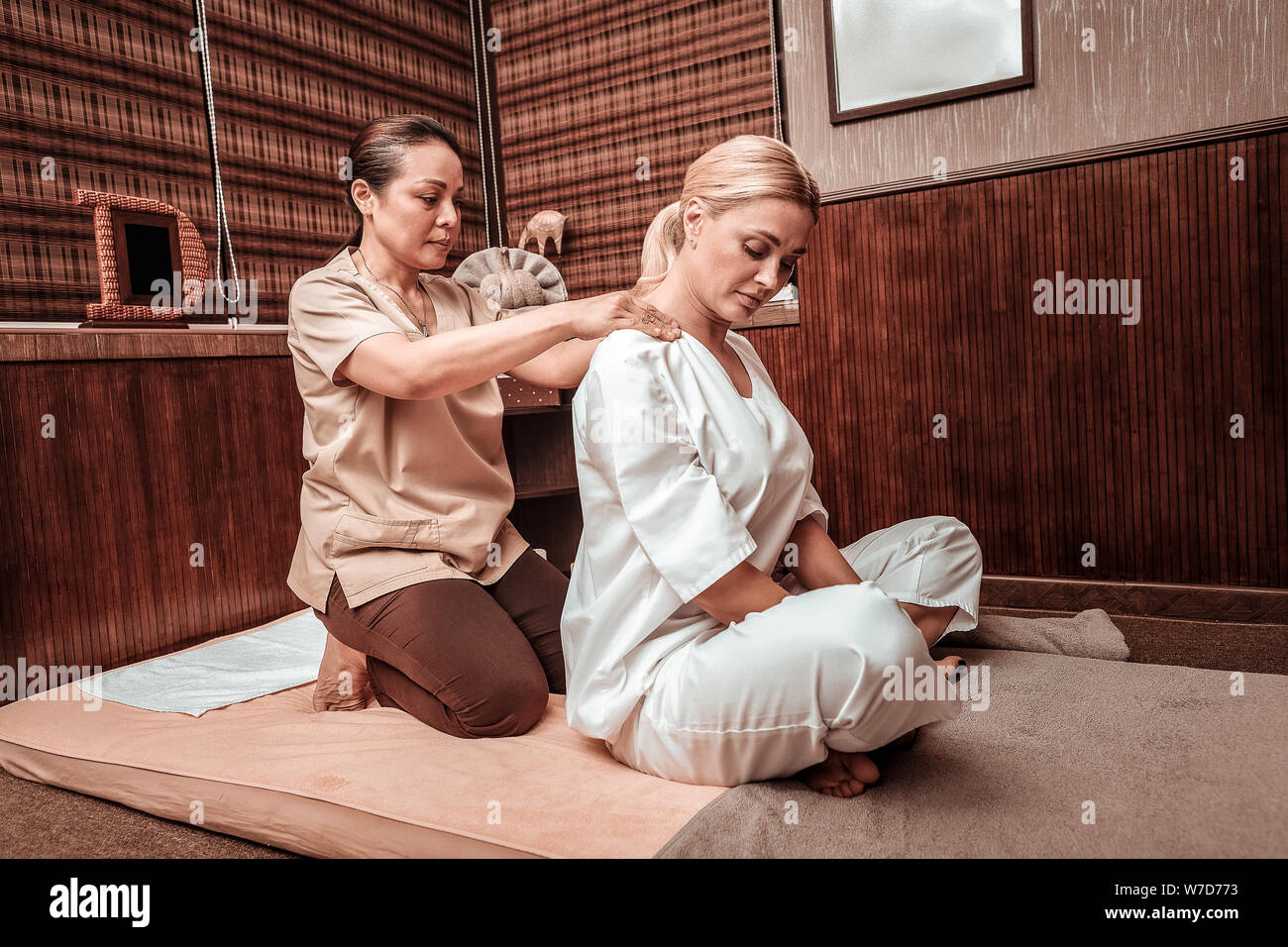 Massaggiatrice professionale lavorando con le spalle del suo cliente. Foto Stock