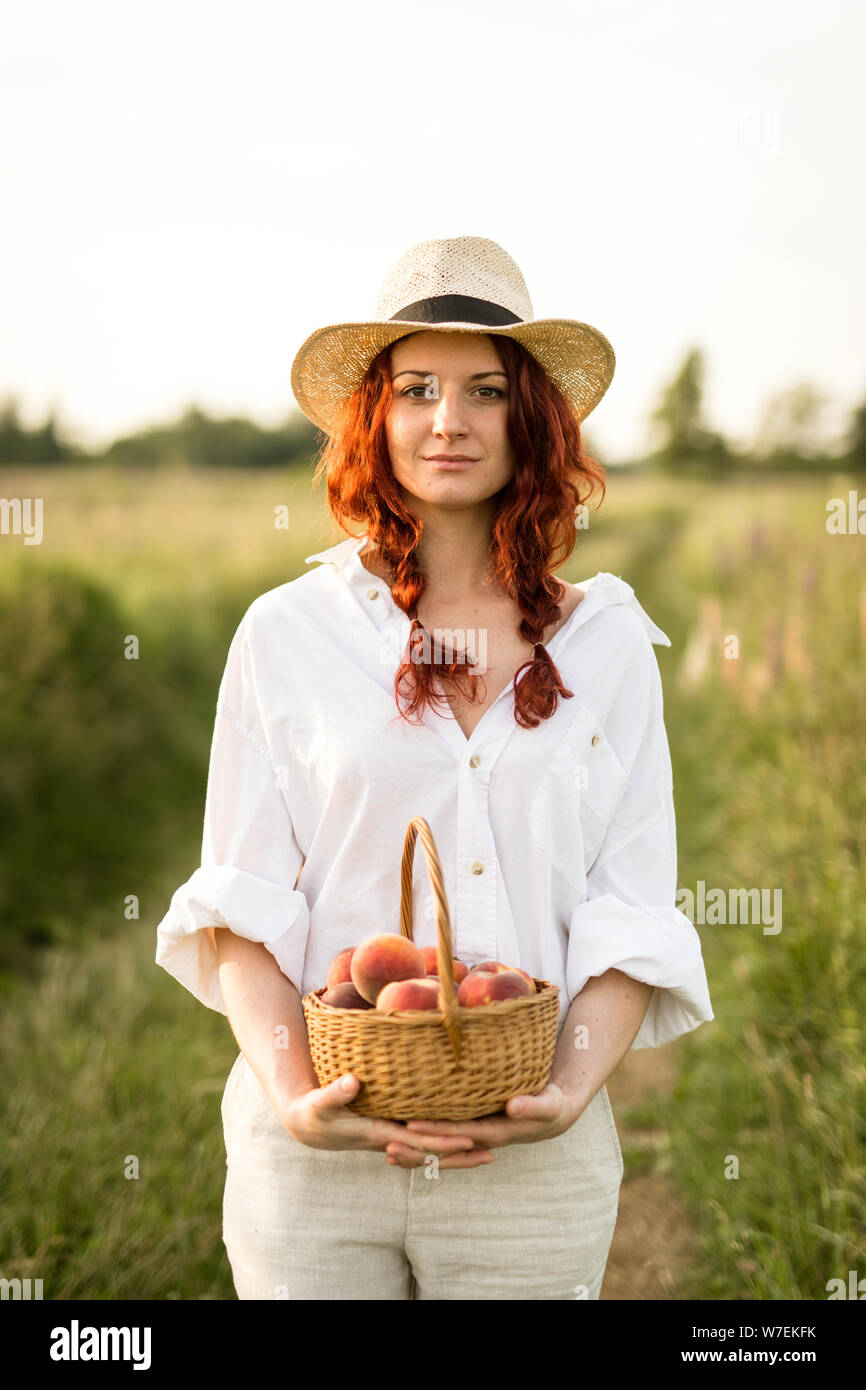 Un bellissimo paese lato ragazza con un paniere di maturazione delle pesche Foto Stock