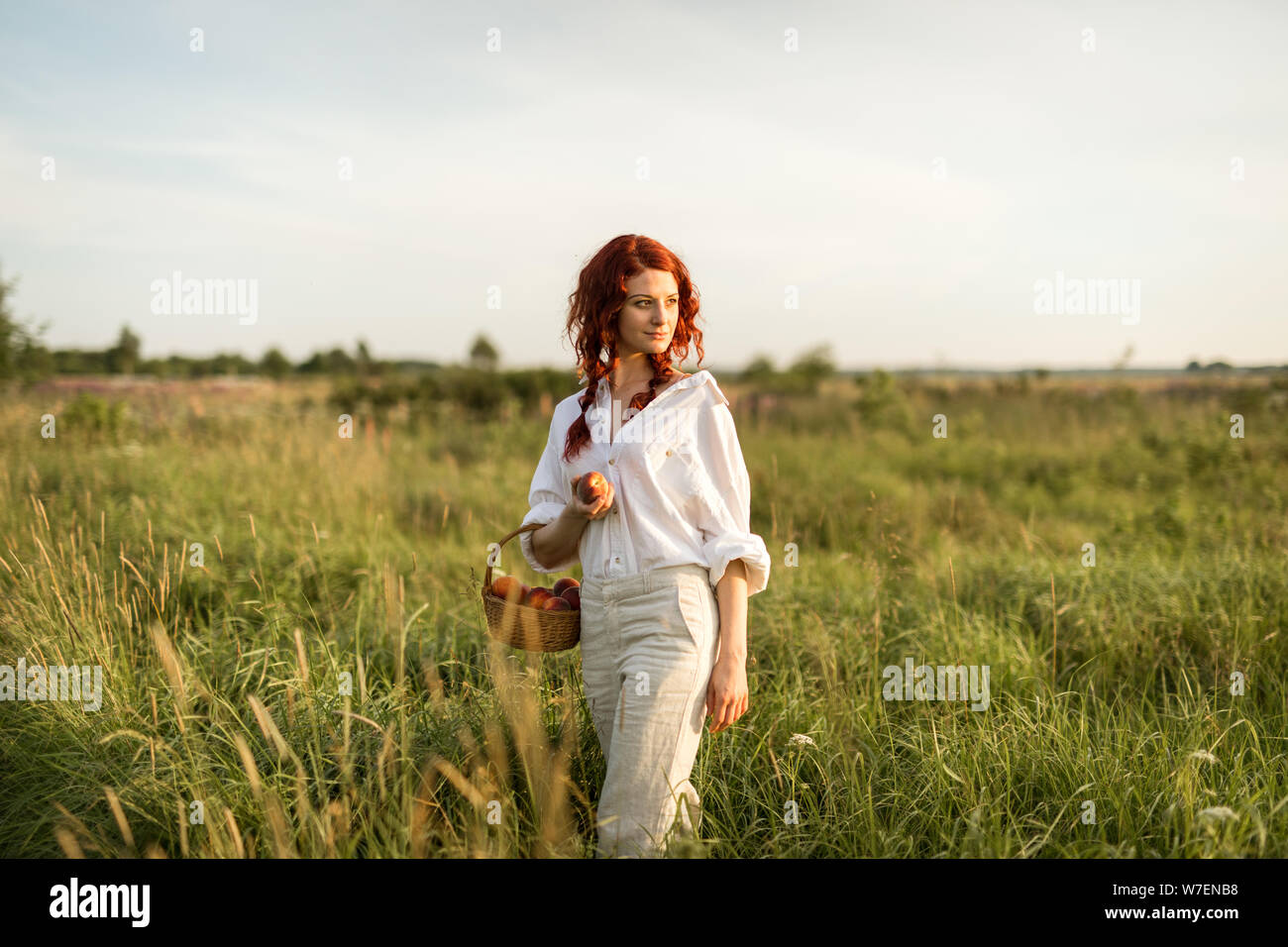 Un ritratto di una giovane donna di rosso in un prato estivo Foto Stock