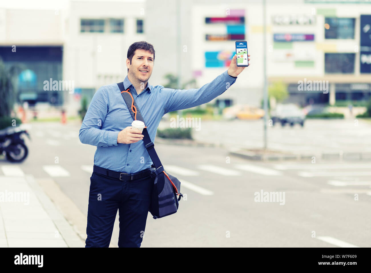 Giovane uomo mediante telefono mobile app in attesa di rideshare - millenaria uomo d affari con mano chiamando il taxi salutando dal marciapiede Foto Stock