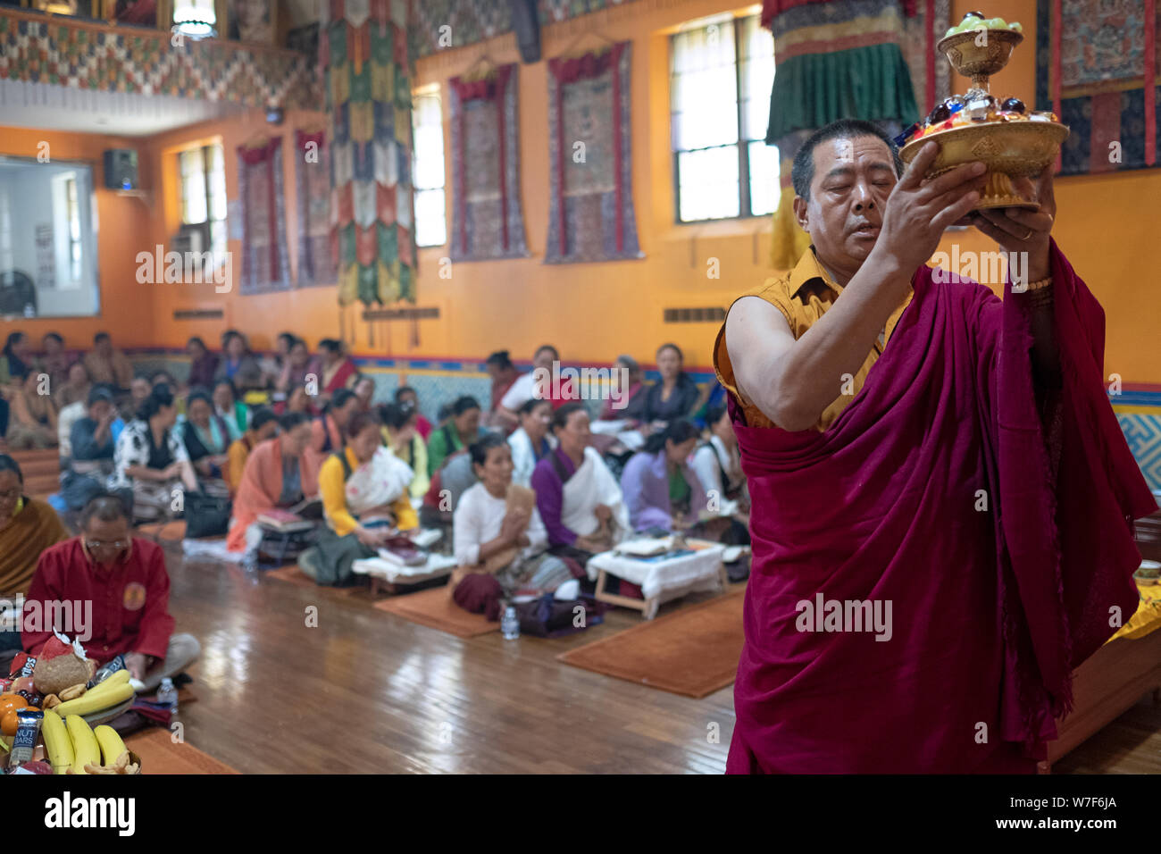 Un Nepalese monaco buddista offre un piccolo vassoio di cibo per la Buddah. Presso lo Sherpa Kyidug tempio di Elmhurst, Queens, a New York. Foto Stock