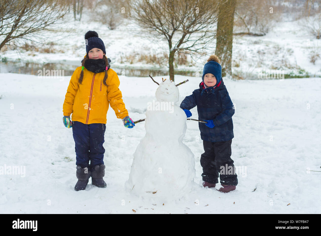 Ritratto di piccolo fratello e sorella. giocare i bambini in inverno. bambini accecato un pupazzo di neve. Foto Stock