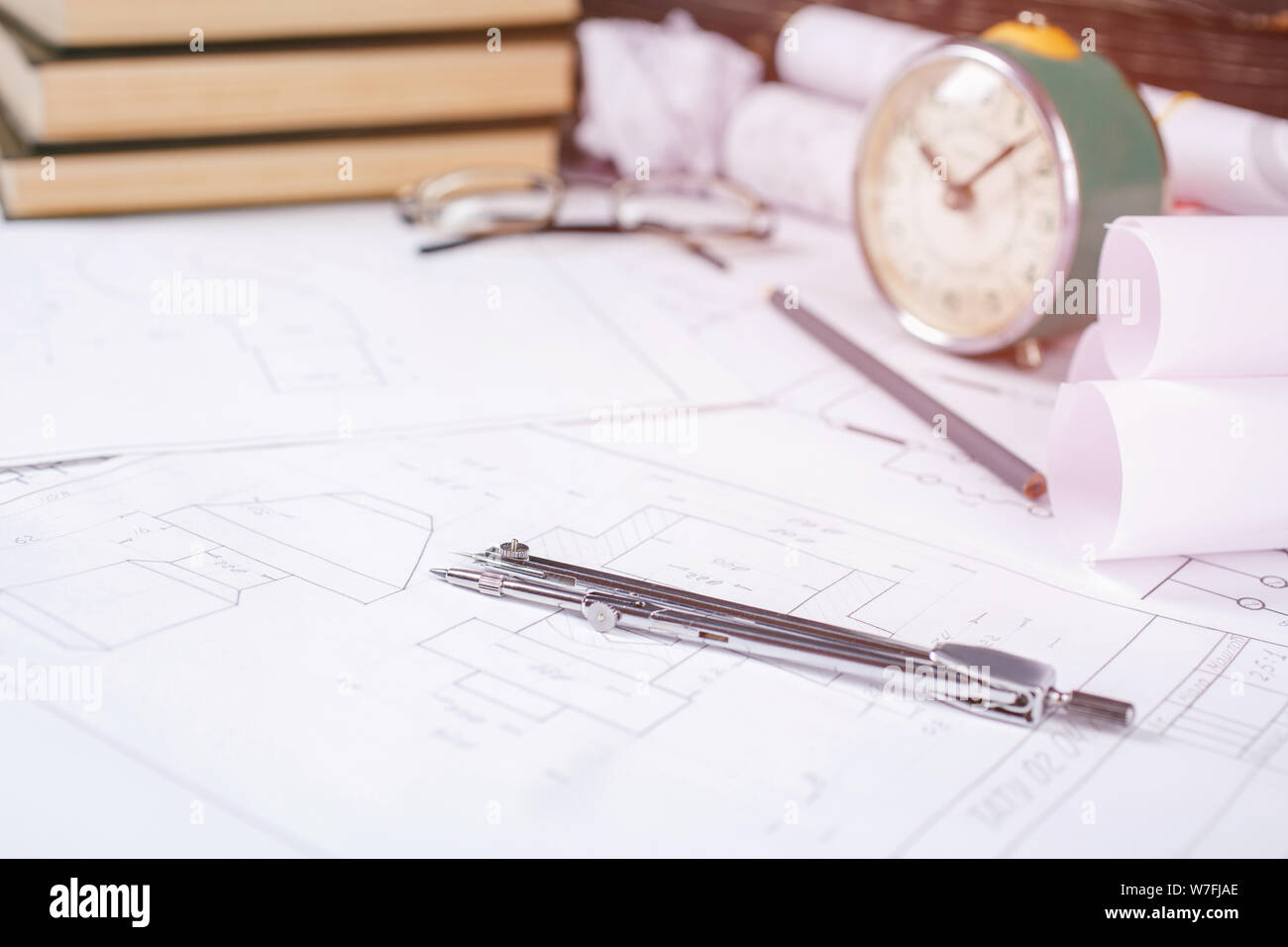 Libri sull'architettura, alcuni disegni sminuzzati, bicchieri sul tavolo dell'architetto Foto Stock