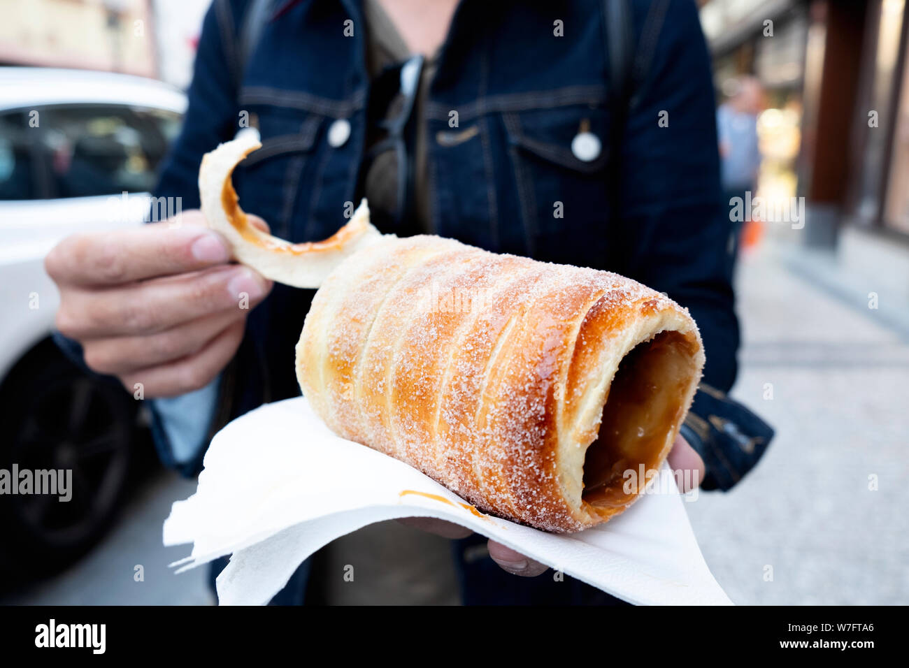 Primo piano di una yougn uomo caucasico mangiando un trdelnik, una tipica torta allo spiedo, nella città vecchia di Praga, Repubblica Ceca Foto Stock