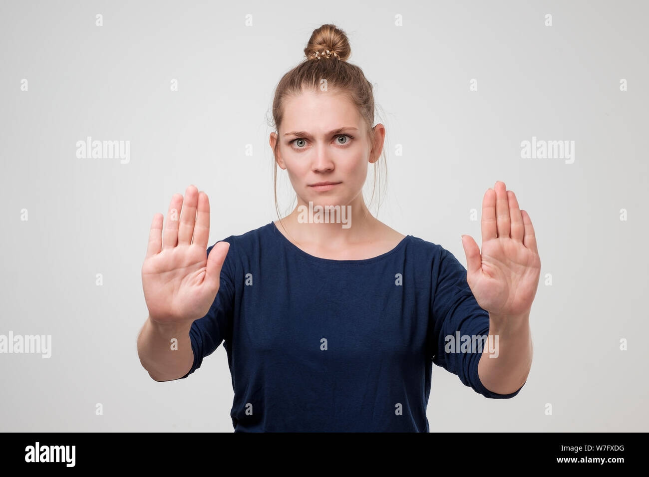 Infelice donna caucasica con sedia bun mostra di arresto o di un numero sufficiente di gesto con la mano, accigliata e esprimendo antipatia. soggiorno lontano da me o non venire clo Foto Stock