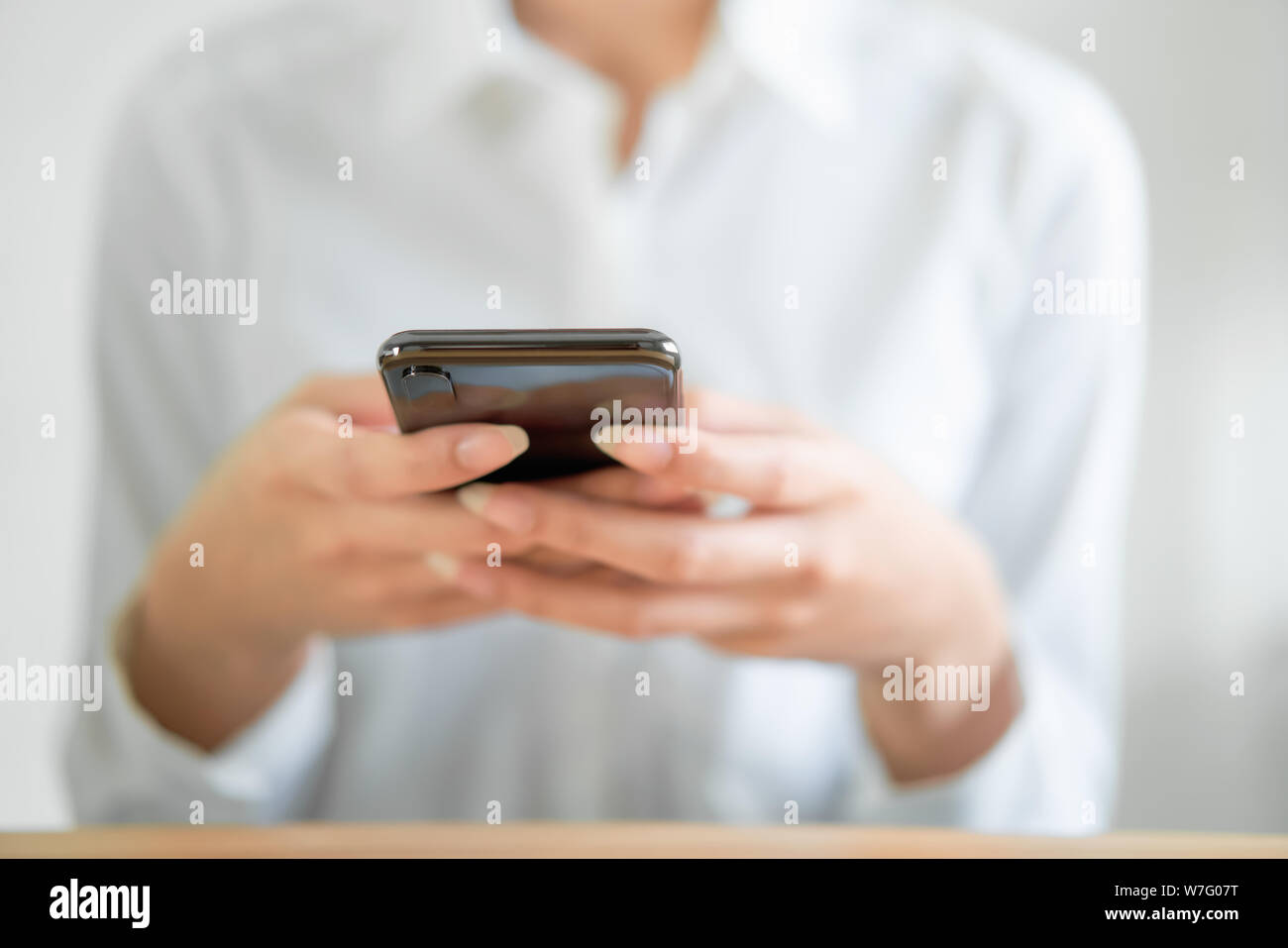 Close-up di mani utilizza lo smartphone su un tavolo di legno e digitando messaggio ai suoi amici. Foto Stock