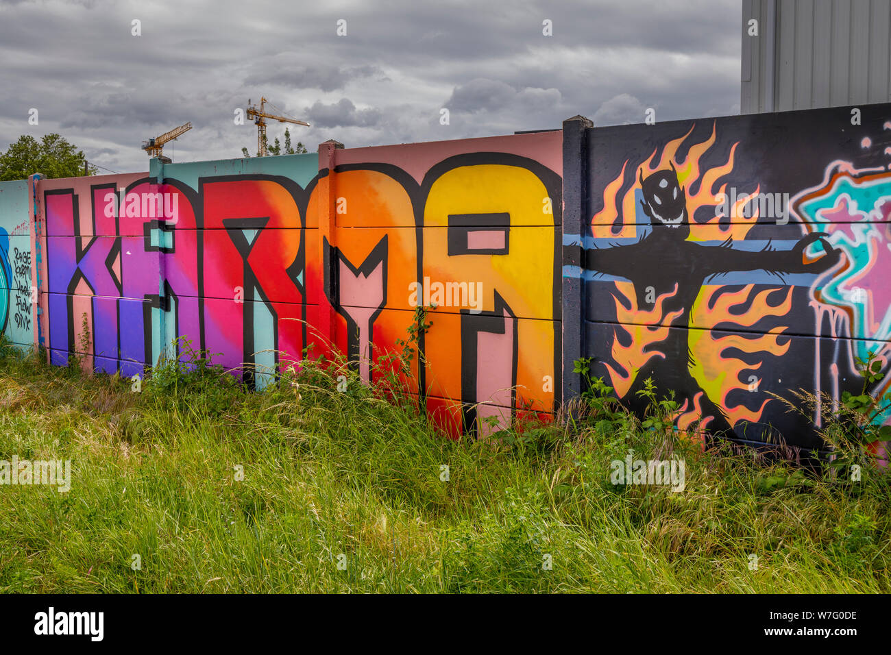 Karma e fiamme di demon grafitti accanto al Quai des Queyries su una palizzata intorno al grande rinnovamento di La Bastide, Bordeaux, Francia. Foto Stock