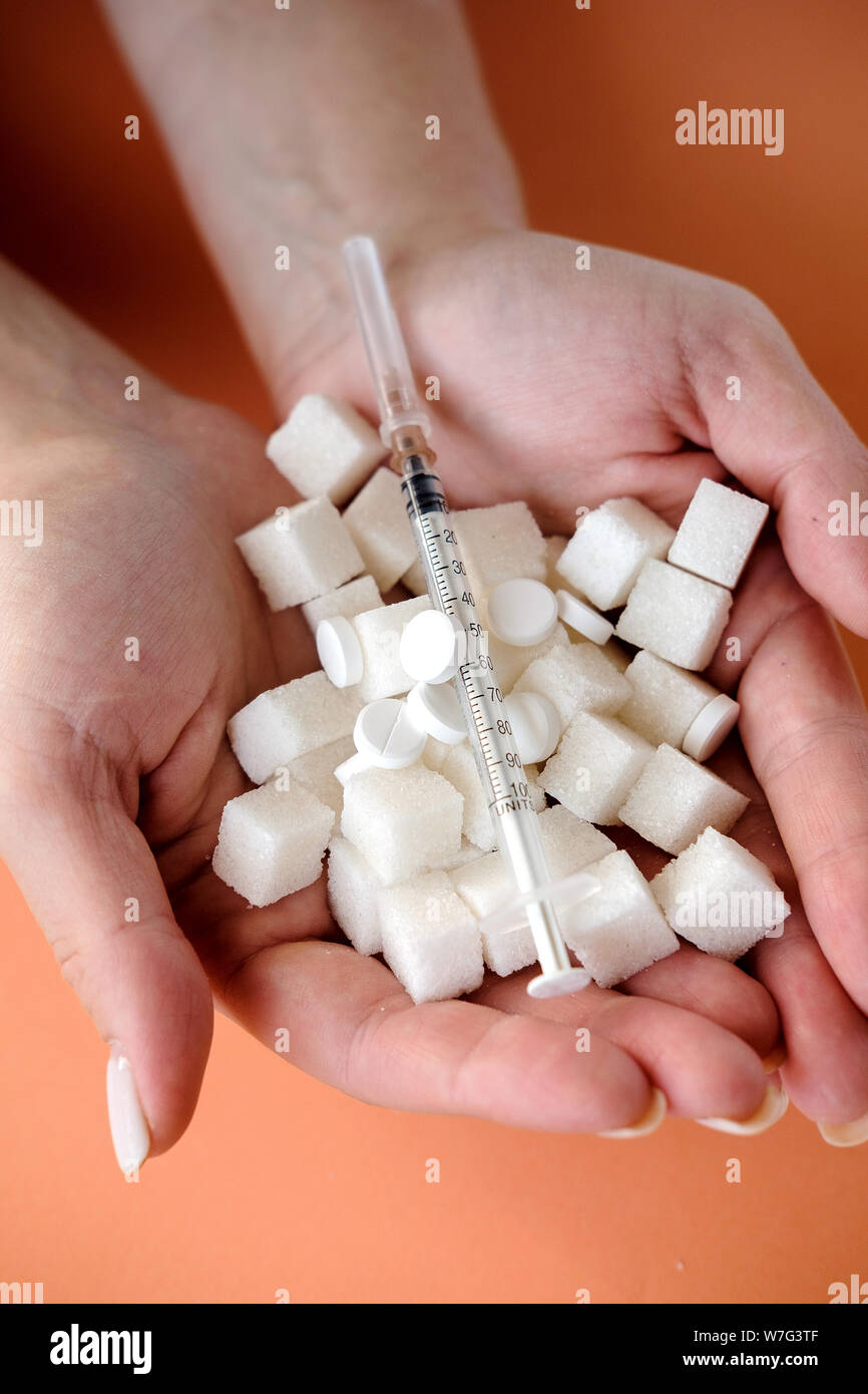 Donna che mantiene lo zucchero bianco cubi e siringa da insulina su sfondo arancione. Il diabete, malattia di zucchero, alimenti dannosi per la salute, la dieta concetto. Spazio di copia Foto Stock