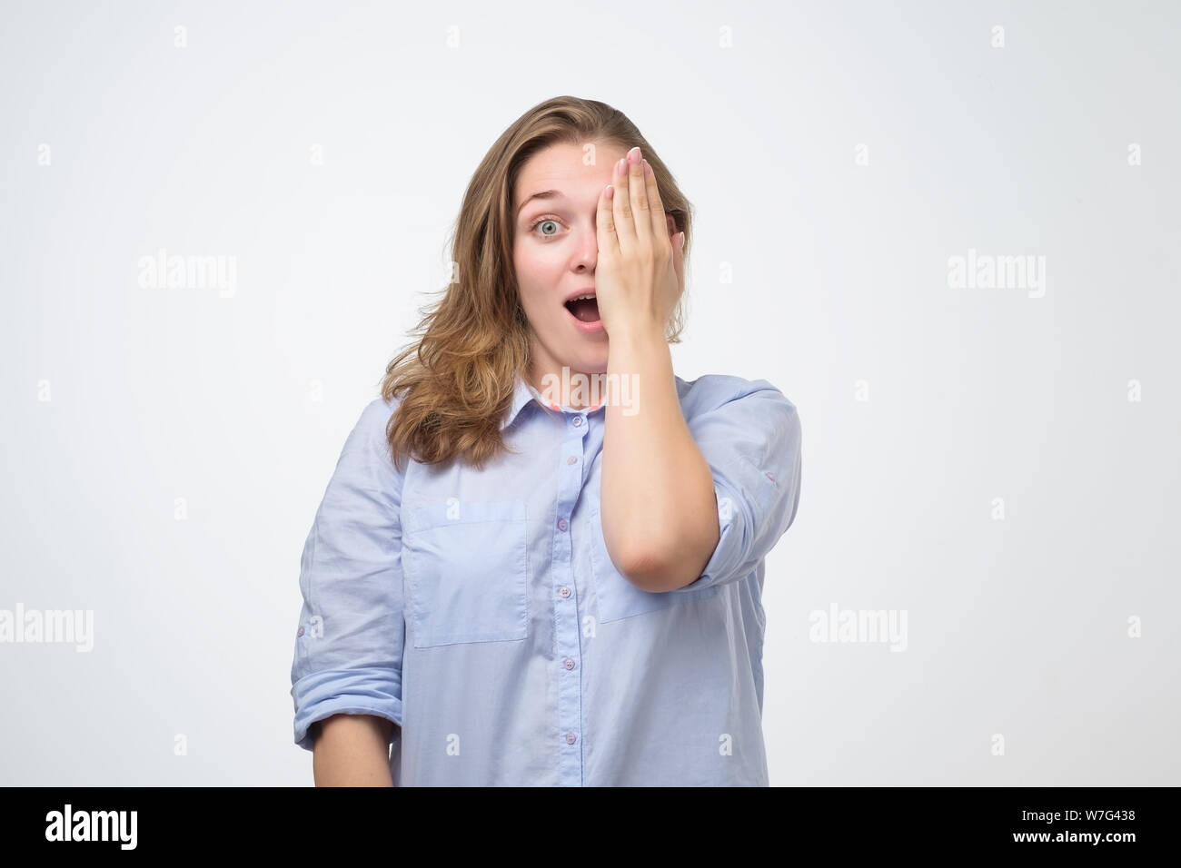 Attraente giovane donna che copre un occhio con la sua mano controllando la sua vista. Viso positivo emozioni umane. Foto Stock