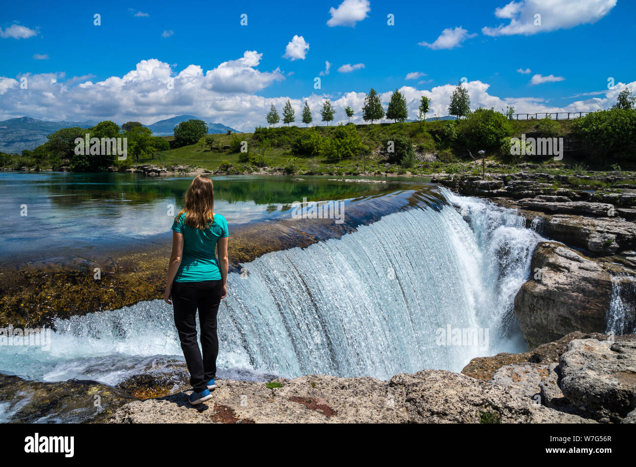 Montenegro, giovane e bella donna bionda in piedi stupiti fragoroso cascate del Niagara in Podgorica, una cascata gigantesca nella spettacolare natura naturale lan Foto Stock