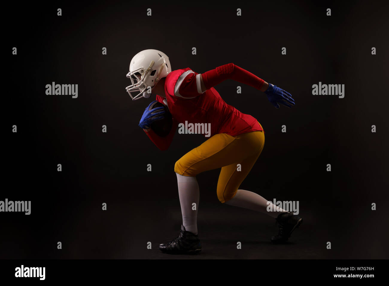 Immagine del lato della donna in esecuzione American giocatore di calcio nel casco in studio Foto Stock