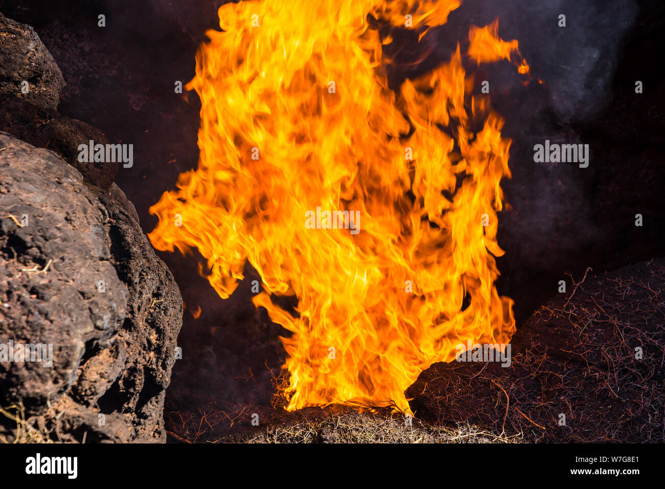 Spagna, Lanzarote, Hot Orange fiamme di fuoco del falò delle balle di fieno in caldo calore terrestre del vulcano timanfaya Foto Stock