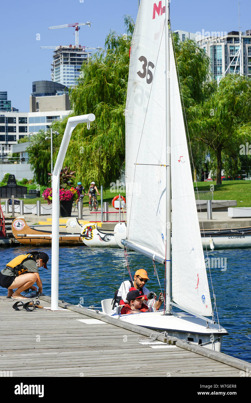Disattivato i ragazzi sono introdotti alla vela, istruttore di vela aiuta i giovani disabili nel ragazzo per il gommone e off per una vela sul Lago Ontario, Canada Foto Stock