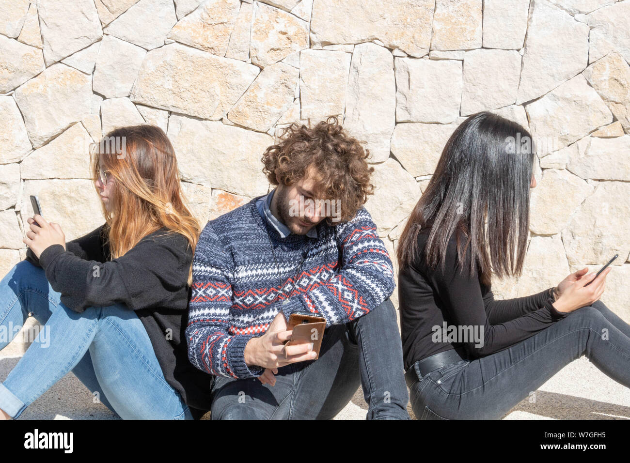 Rimaniamo in contatto costante grazie all'uso di smartphone, collegato allo stile di vita giovane adulto gruppo su reti sociali seduto per terra con il Foto Stock