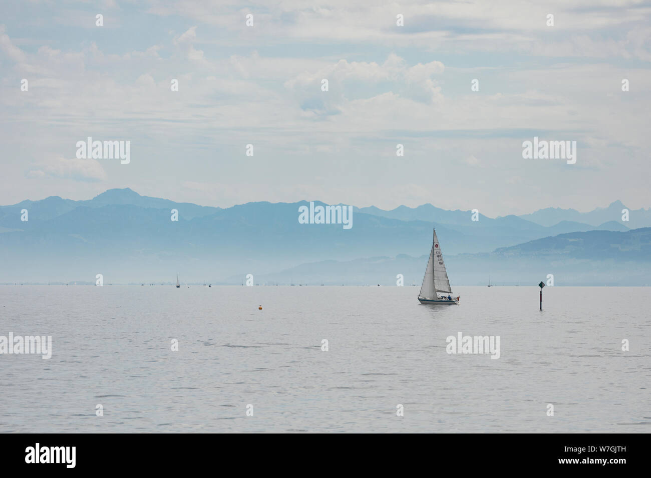 Una barca a vela scivola nella parte anteriore delle Alpi sul Lago di Costanza (Bodensee) su un giorno di estate in Friedrichshafen, Germania. Foto Stock