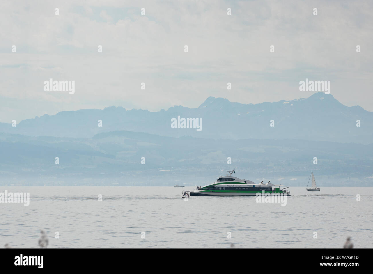 Un tour in barca passa le Alpi sul Lago di Costanza (Bodensee) prima di entrare in porto in un giorno di estate in Friedrichshafen, Germania. Foto Stock