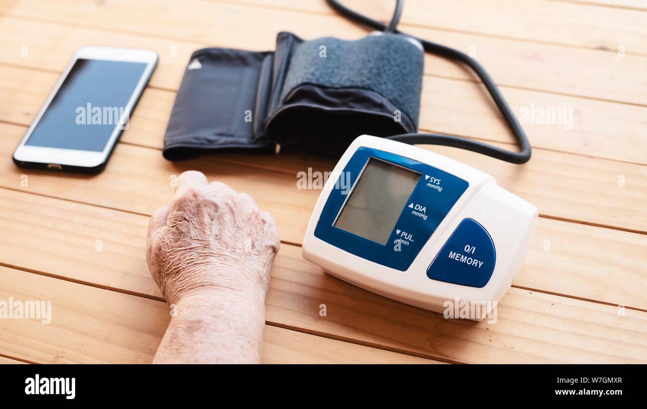 Old Lady è in fase di controllo della pressione sanguigna utilizzando monitor della pressione del sangue kid set - Persone con la salute cura medica di strumentazione concept Foto Stock