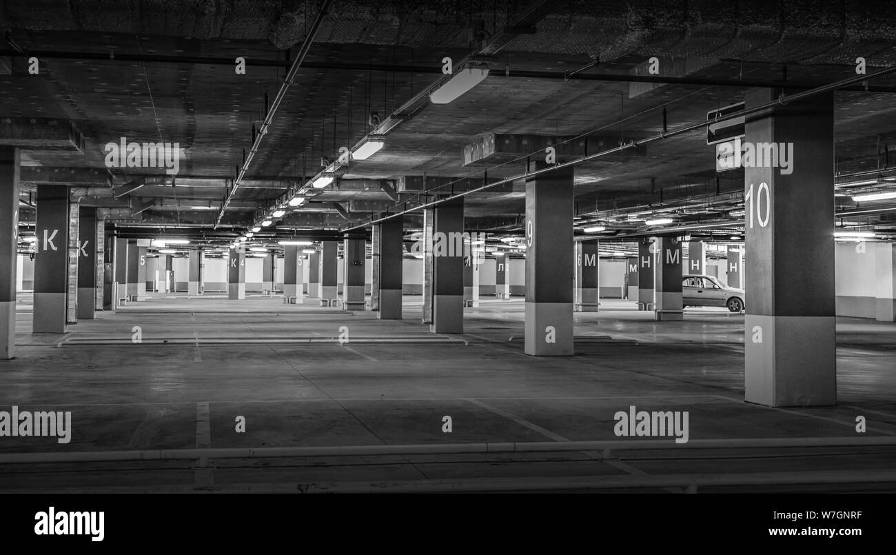 Una schifezza, fiocamente illuminate vuoto parcheggio garage con le luci della lavagna luminosa e di un segnale di uscita che pende dal soffitto. Foto Stock