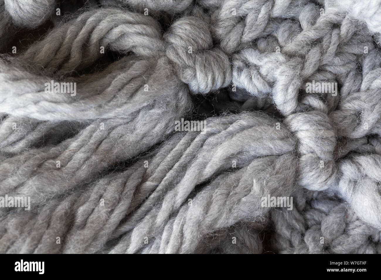 Maglia sciarpa di lana con fiocchi, macro. Grigio morbida lana merinos sfondo, closeup. In autunno e in inverno, laici piana. Scandinavian stile minimal. Foto Stock