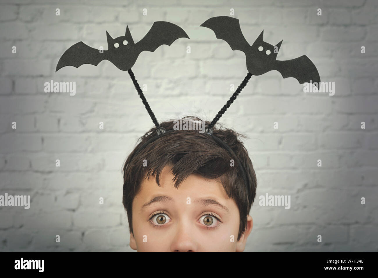 Happy Halloween.divertente bambino con halloween vampiri oltre sulla sua testa contro Sfondo mattone Foto Stock