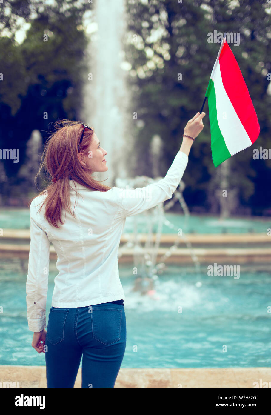 Giovane donna che guarda verso l'alto sulla bandiera ungherese dell'Isola Margherita fontana, Budapest, Ungheria Foto Stock