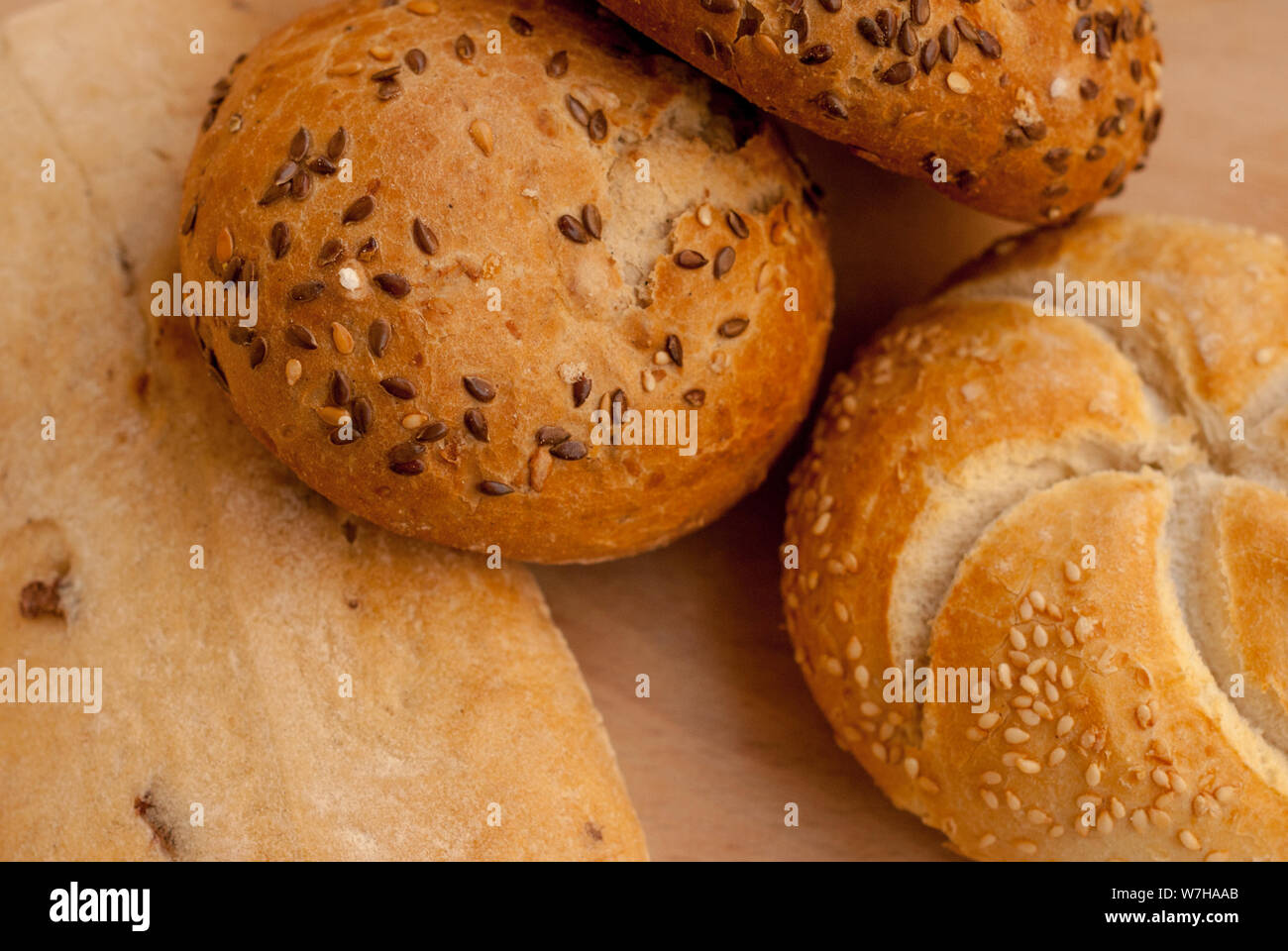 Ciambelle di pane farcito con semi di girasole con altre focacce di pane in background Foto Stock