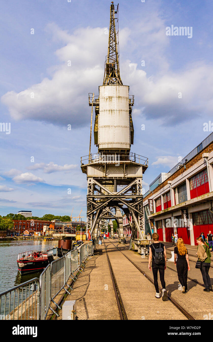La gente camminare passato Bristol M-Shed museo l'Harbourside accanto a 1950 electric gru portuali. Bristol, Regno Unito. Luglio 2019. Foto Stock